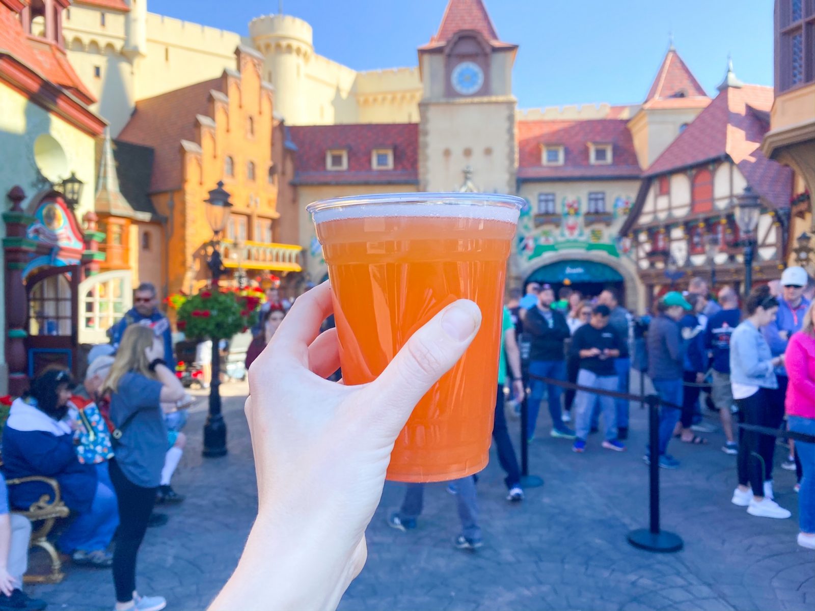 woman holding a yellow glass of grapefruit beer while drinking around the world at epcot