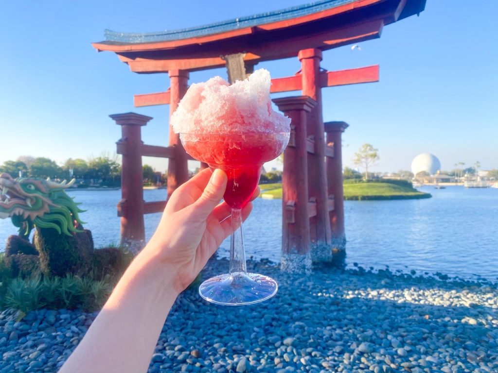 photo of a beautiful drink being held up in front of the Torii gates in Japan, definitely among the best things to do at Epcot
