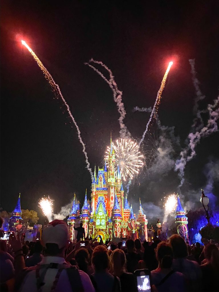 brightly colored castle with fireworks going off behind it