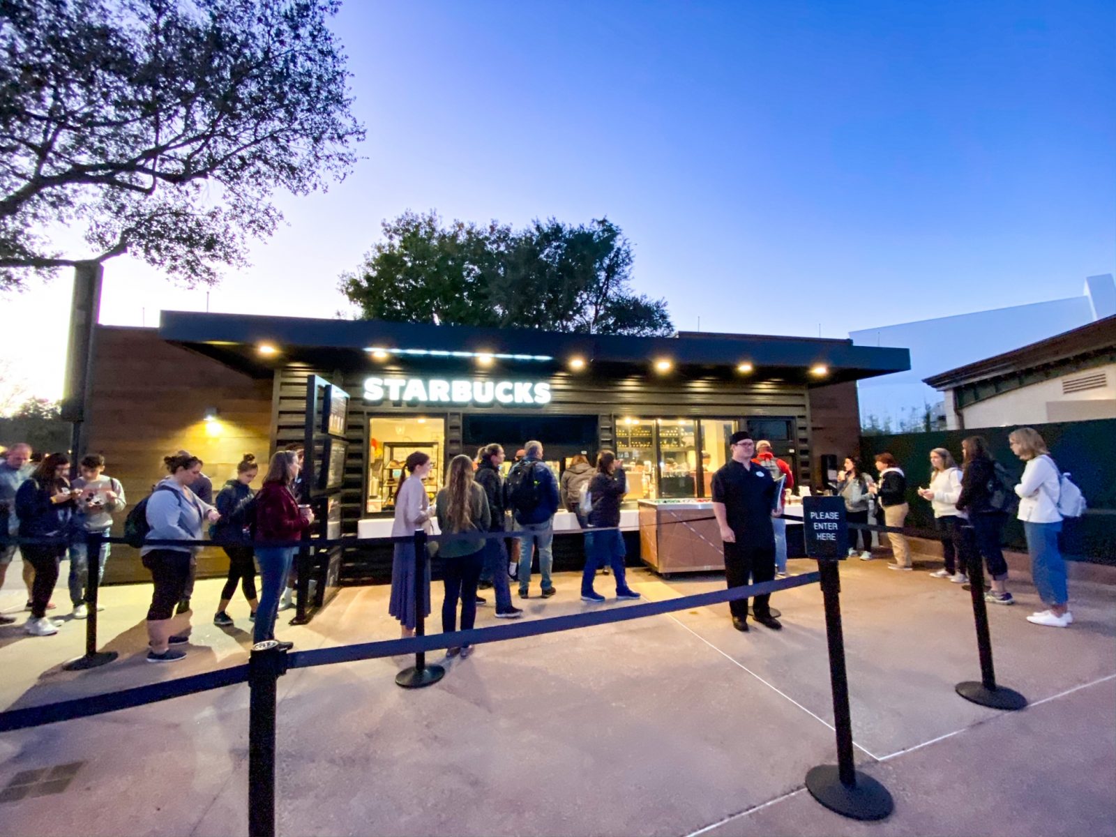 A small queue of patrons wait at the Epcot Starbucks kiosk, a modern and efficient design.