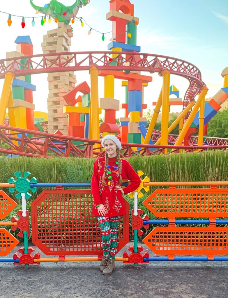 woman standing in front of Slinky Dog Dash in Toy Story Land wearing a festive Christmas outfit 