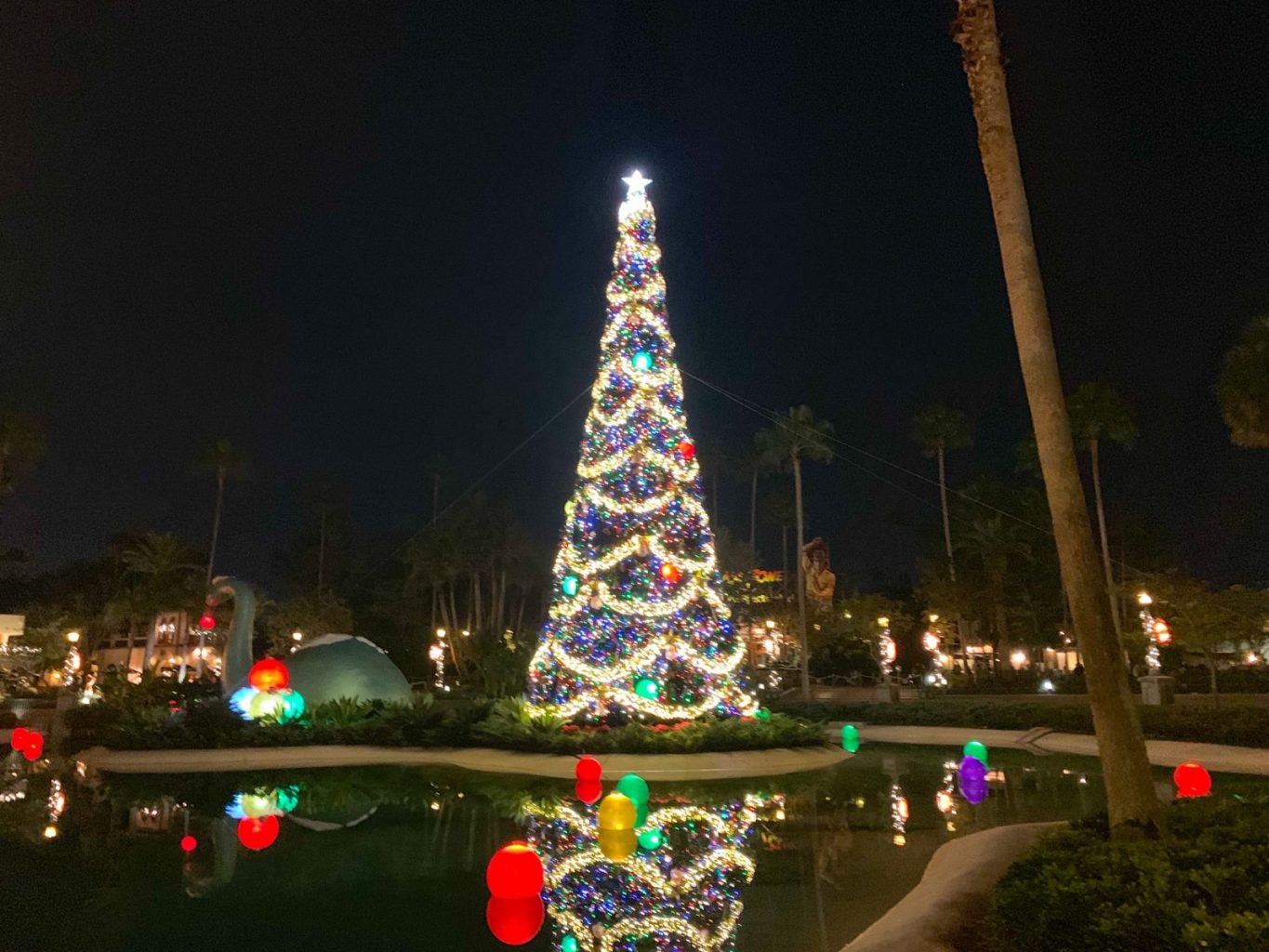 night view of a giant Christmas tree in the middle of Echo lake in Hollywood Studios