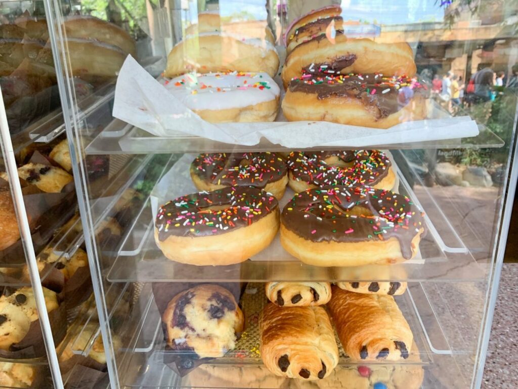 iced doughnuts and chocolate croissants in a stacked display case
