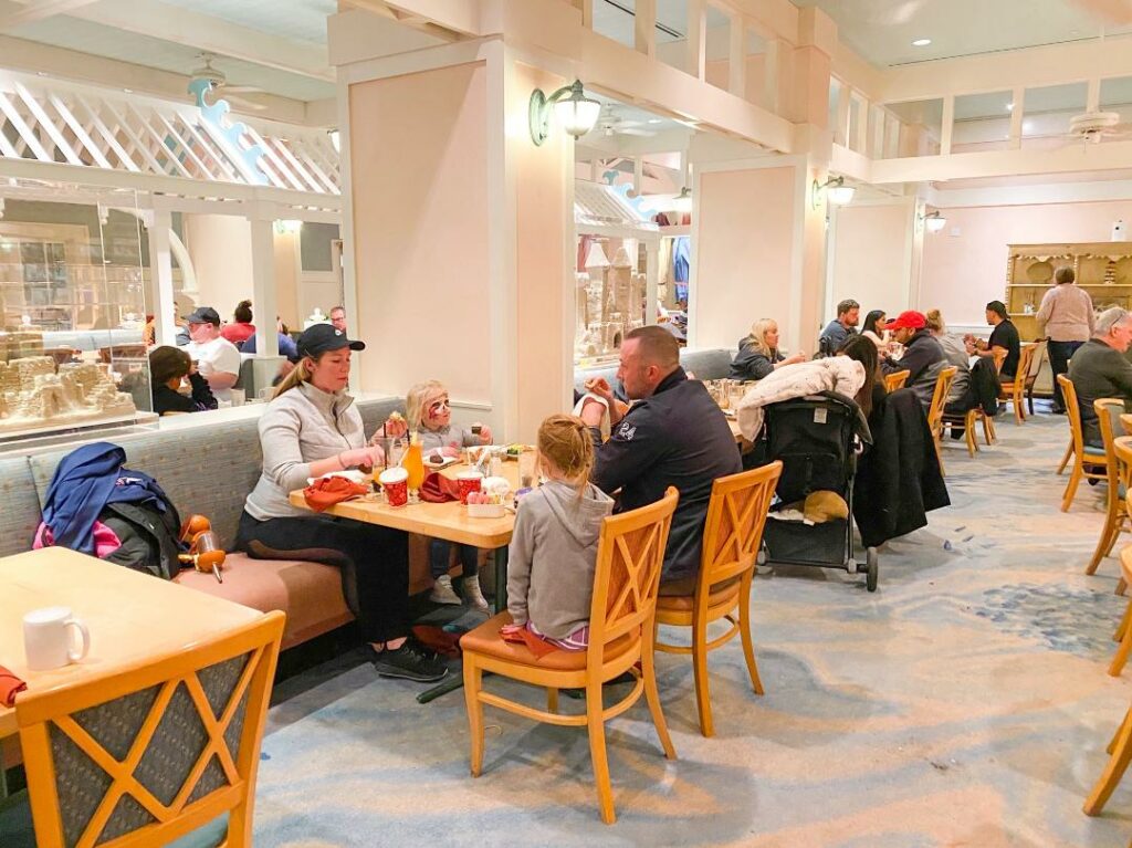people eating at wooden tables and chairs in pink and white restaurant cape may cafe best breakfast at Hollywood Studios 