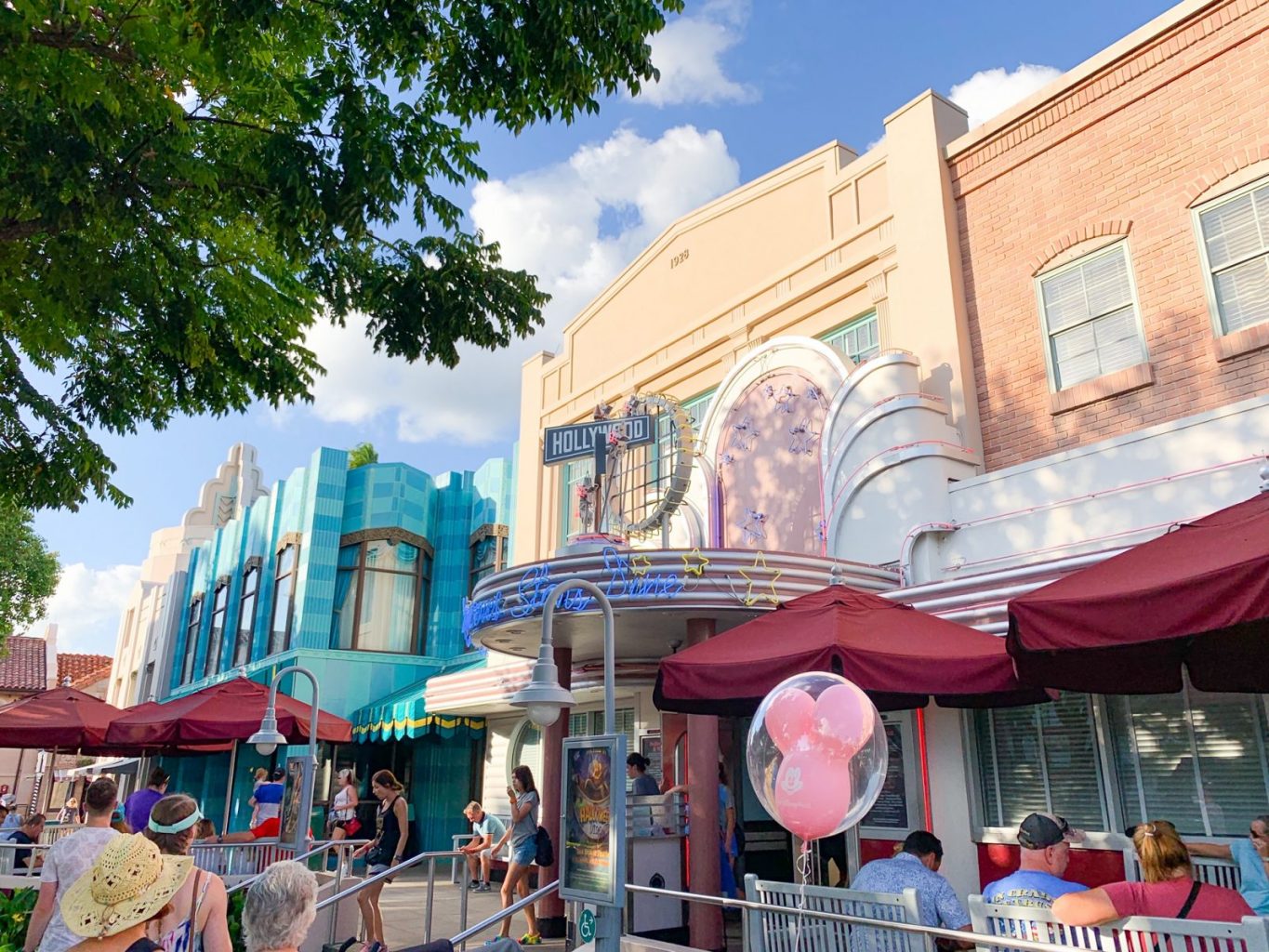 city style buildings with people and a pink mickey balloon in front of it 