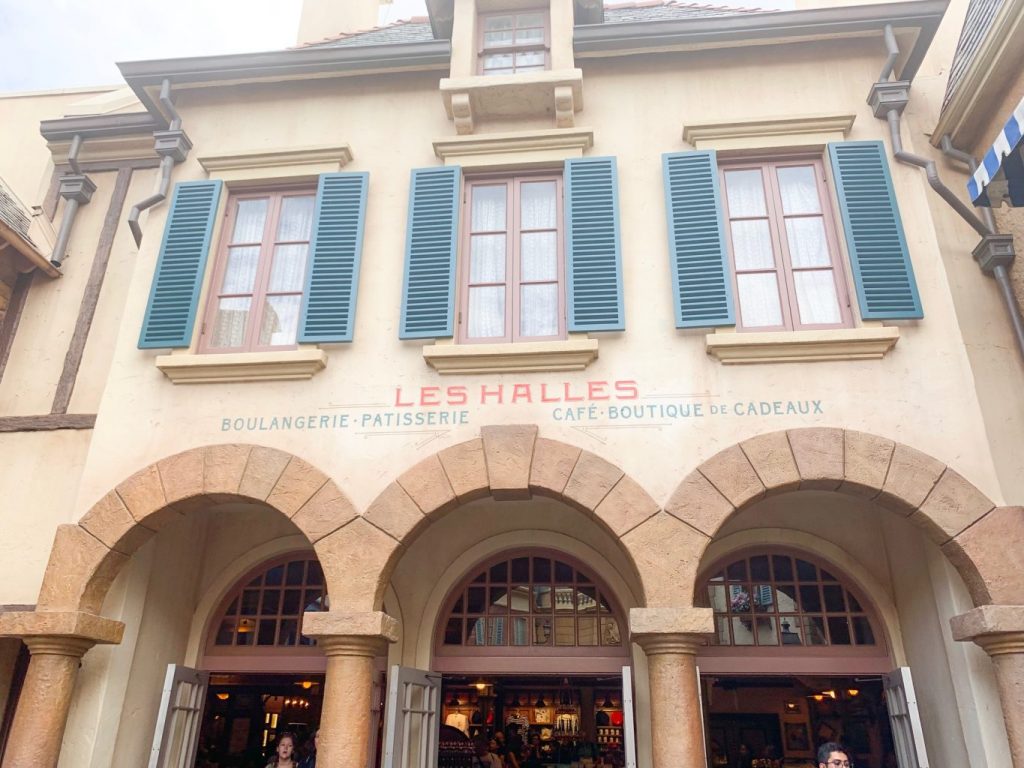 cream colored building with blue shutters over archways for entrance to cafe 