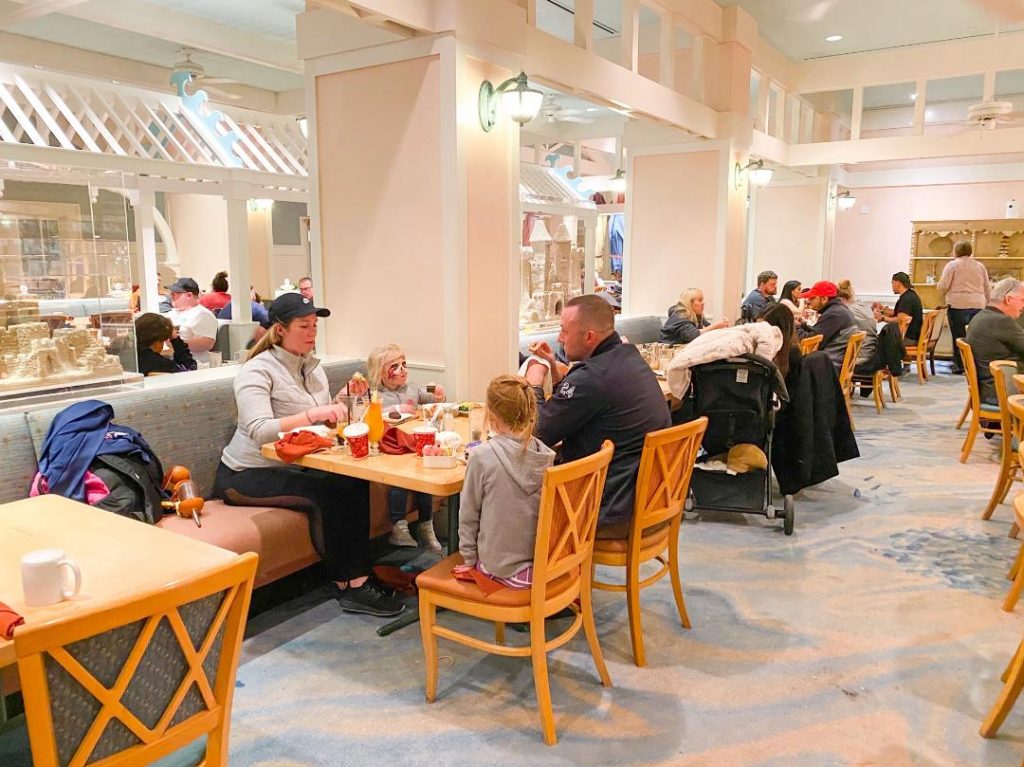 people eating at tables and chairs in white and light pink restaurant 