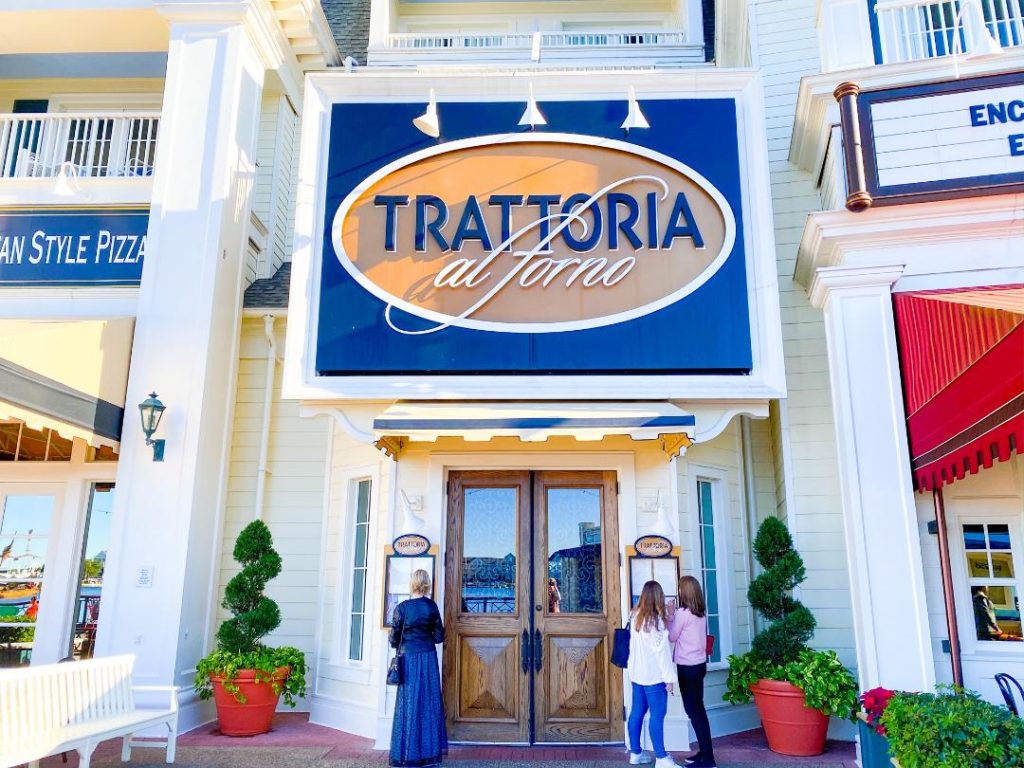 white building with bright blue and tan sign for italian restaurant with people at door 