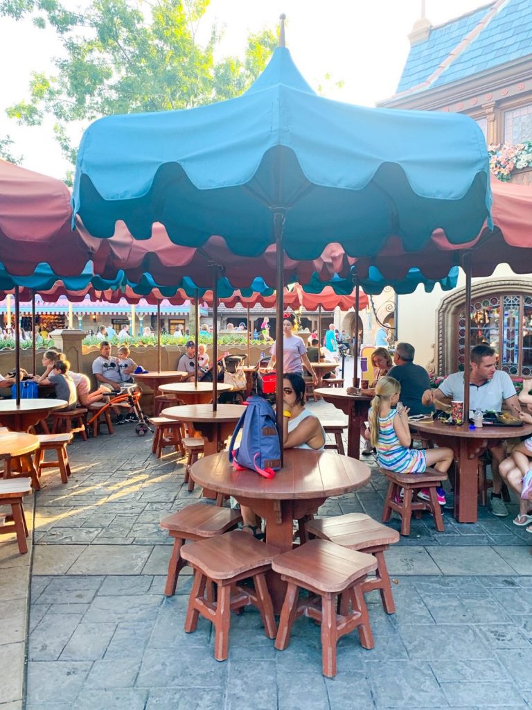 woman sitting out an outside quick service food and beverage table in Magic Kingdom