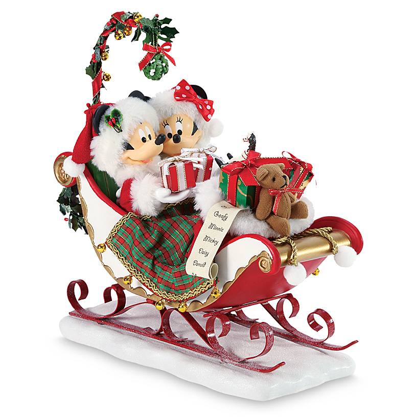Mickey and Minnie Mouse sit in a sleigh with presents and mistletoe hanging above them
