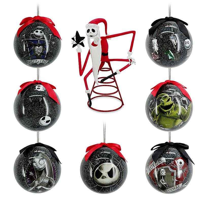 Jack Skellington in a santa suit sits on top of a tree topper with seven nightmare before christmas ornaments around him