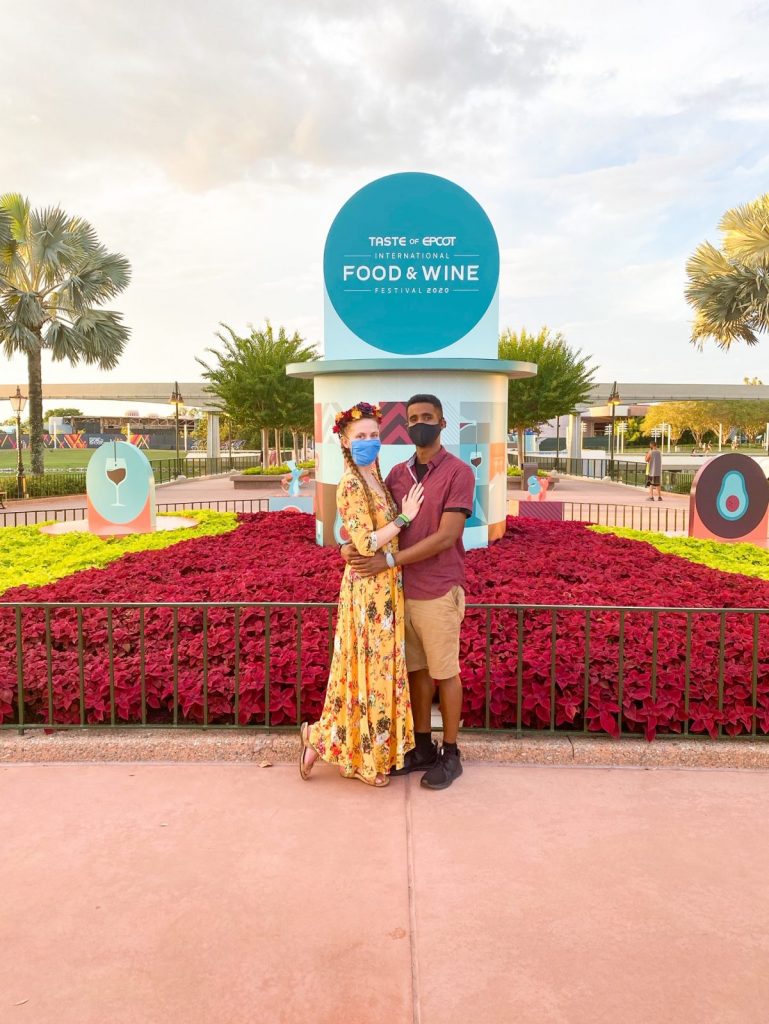 couple standing in front of the food and wine sign at epcot
