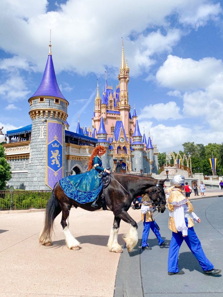 merida riding a horse in front of Cinderella's castle