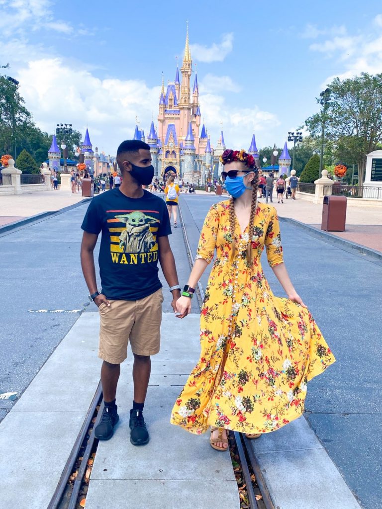 couple walking down main street in front of the castle while wearing their magic bands