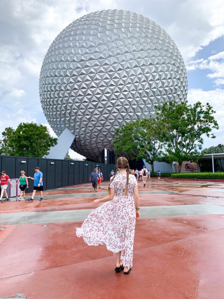 woman standing in front of the Epcot ball