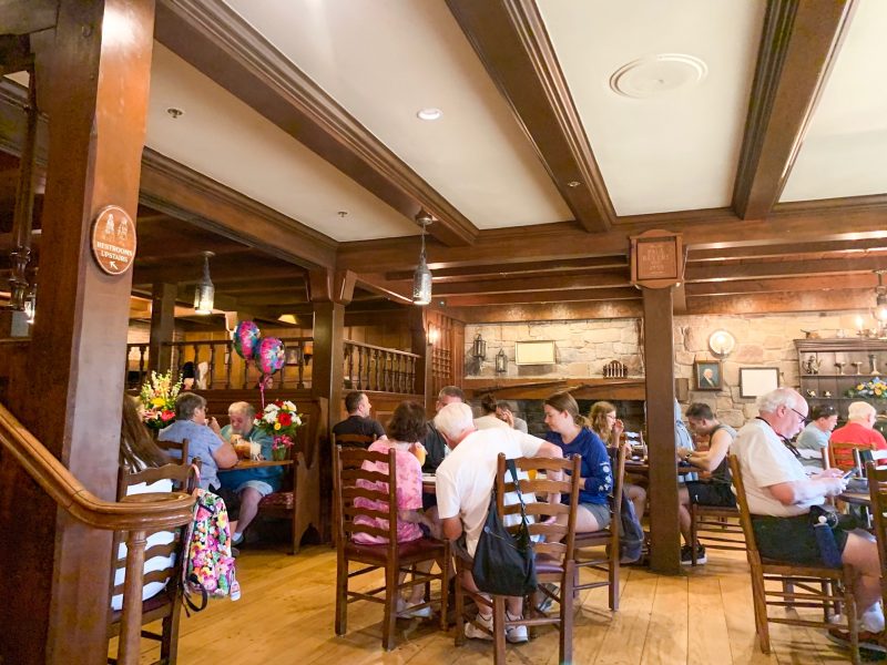 inside of liberty tree tavern restaurant in disney with wooden floors and furniture and people eating