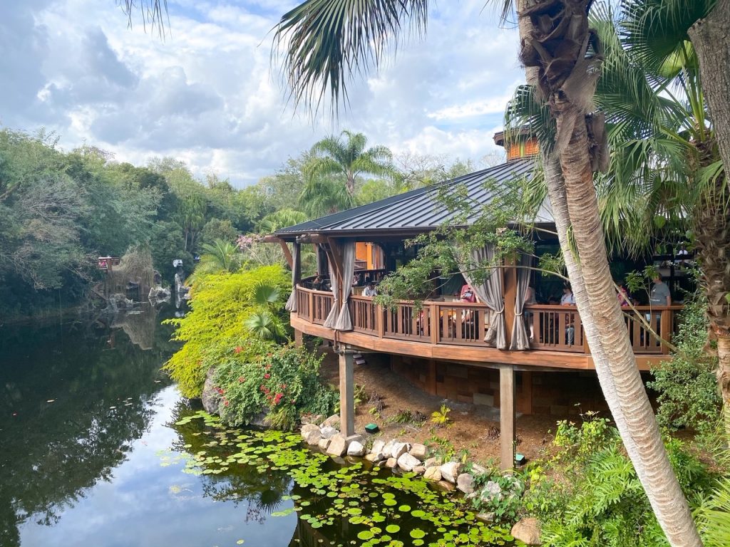 circular thatched building over the water and hidden in the trees outdoor dining at disney 