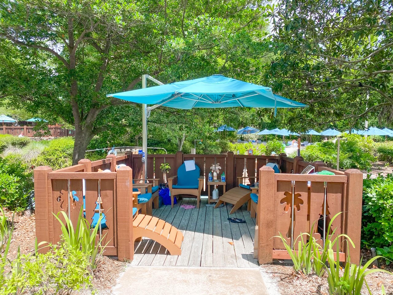 patio with a blue umbrella, lounge chairs, and trees