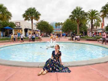 woman sits in front of fountain at Disney Springs