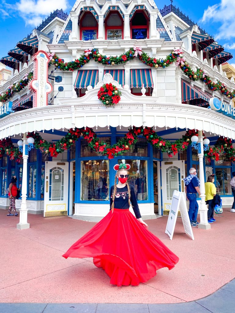 A woman in a red skirt in front of the Confectionary decorated for Christmas