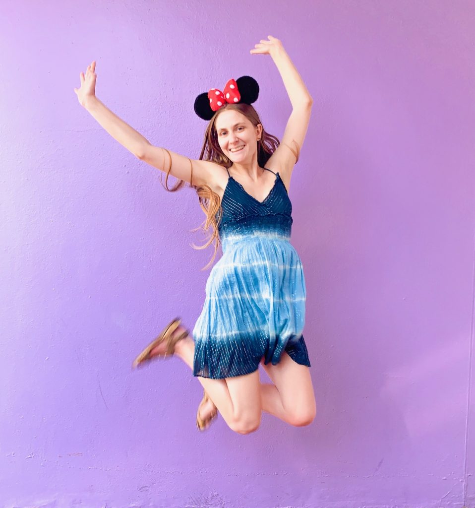 woman jumping in front of the purple wall at Magic Kingdom
