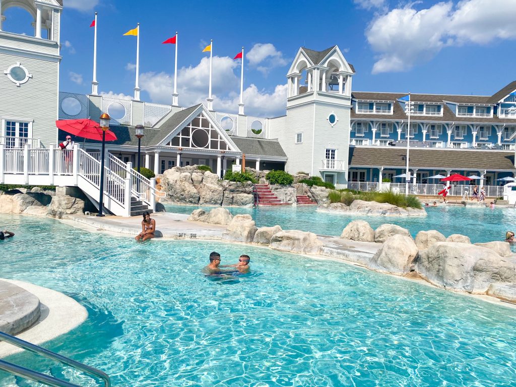 family enjoying a blue pool with hotel in the background