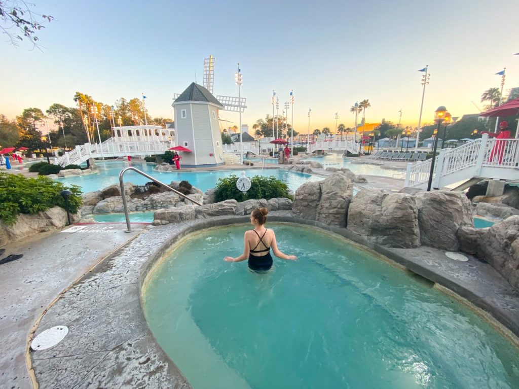 Victoria stands in a hot tub, overlooking a larger pool at a resort that you too can stay at when following the break down of how to use rental points in this David's DVC rental review. 