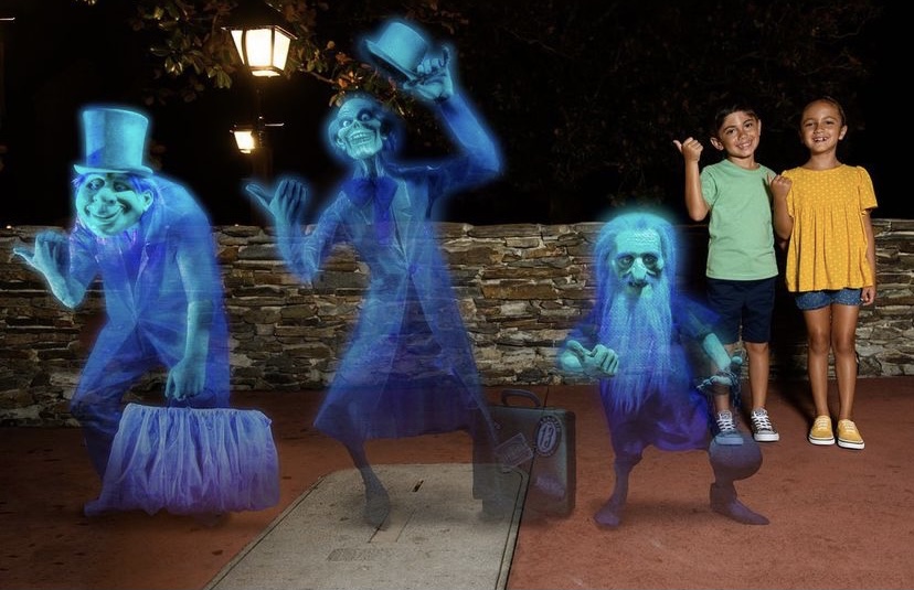Two kids stand by the hitchhiking ghosts of Haunted Mansion, which is a photo feature now on Magic Kingdom Genie+