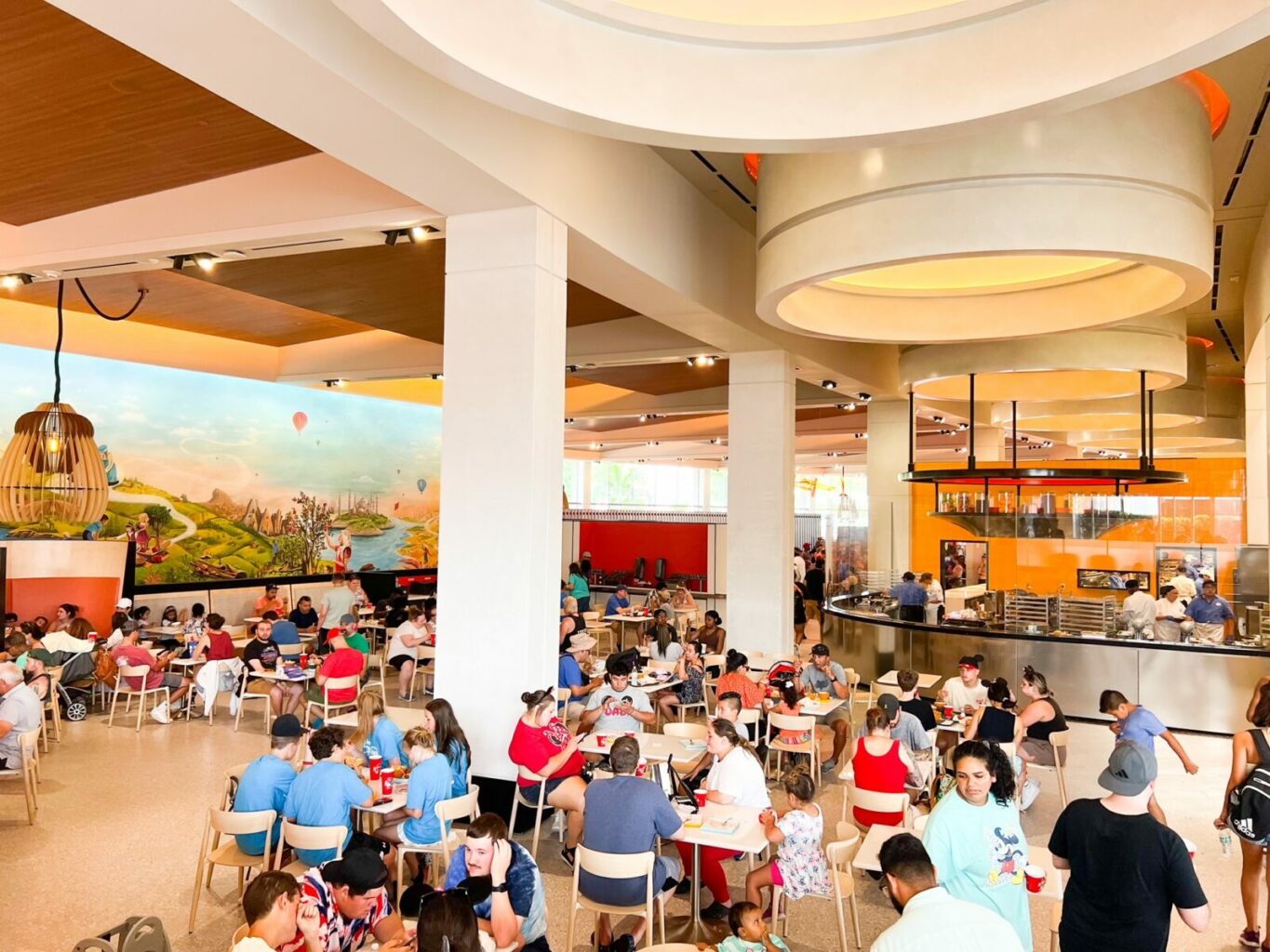 people sitting at tables and eating with large painted mural in the background connections epcot quick service