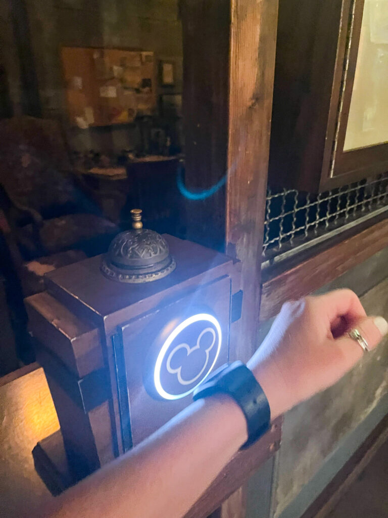person touching disney magic band to lit up touchpoint
