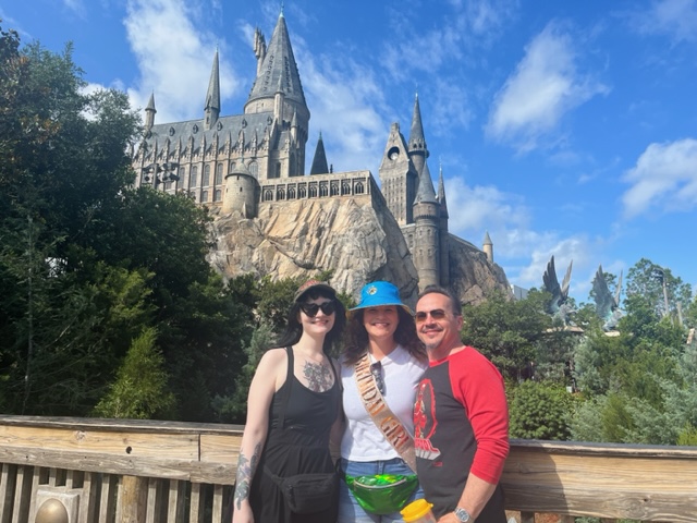 A group of people in hats and sunglasses stand in front of Hogwarts, which is one of the best rides at Universal Orlando.