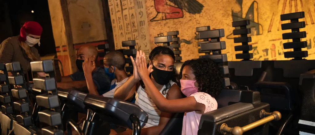 A family high fives each other after conquering the mummy in Universal, which is an indoor, dark coaster that features fire and a curse! 