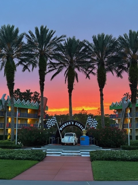 sunset behind trees over a white car for theming at all-star movies resort