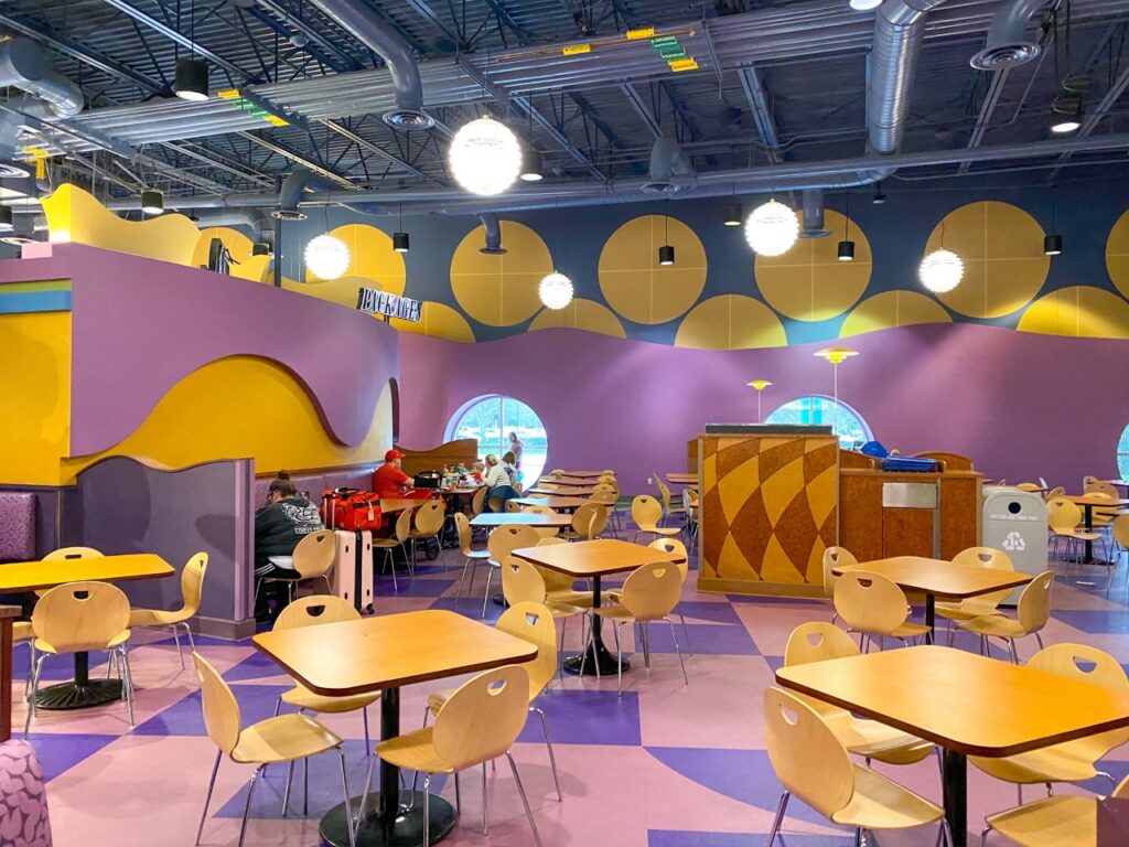 people eating at dining tables and empty tables in pop century food court 