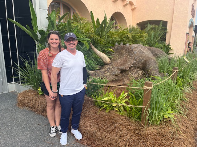 A couple stands in front of the Jurassic Park tribute store, hand in hand: movie buffs often prefer Universal in the Disney World vs. Universal Studios debate because of props and tributes like this. 