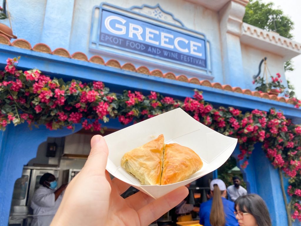 A hand holds up some yummy greek food at the Greek pavilion at Epcot's food and wine festival: Disney has great dietary options! 