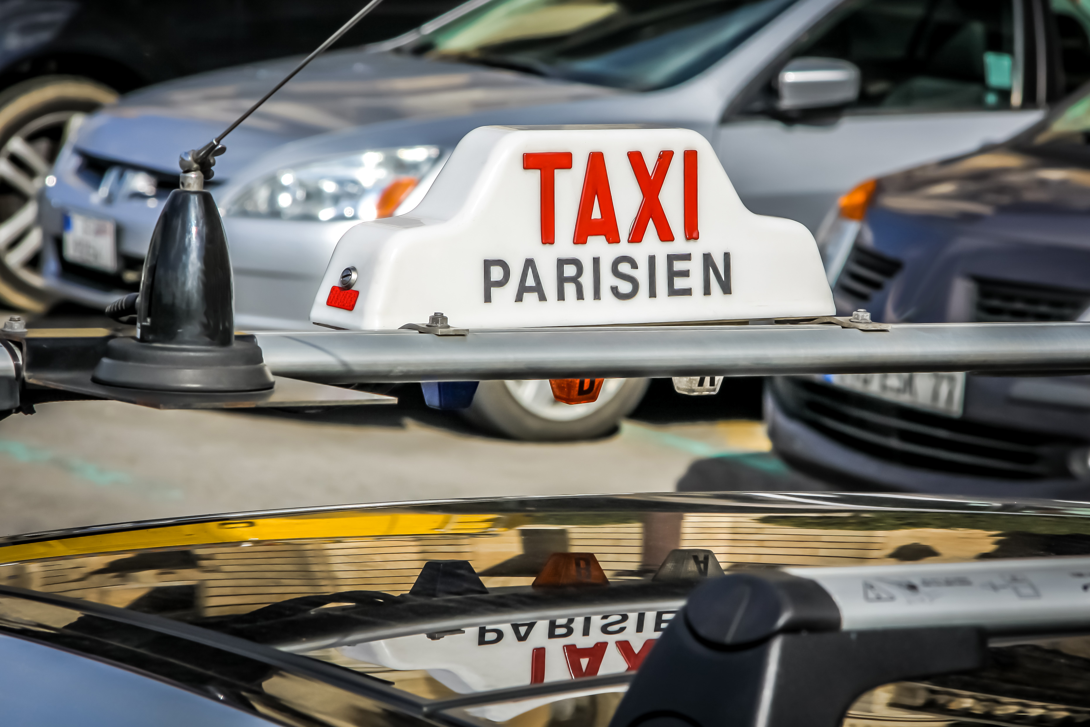 white taxi Parisien sign on top of taxi car Charles de Gaulle to Disneyland Paris 