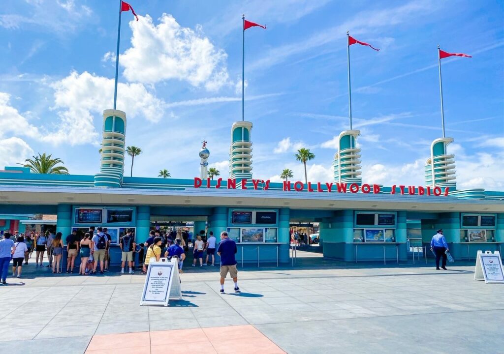The entrance to Hollywood Studios is iconic with its red lettering, tall flags, and retro blue ticket booths.