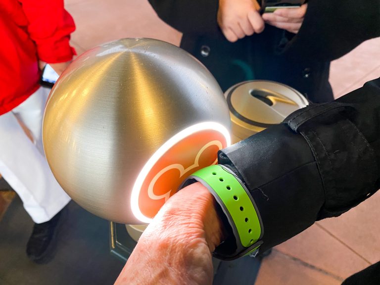 An individual scans their green wrist band with their Disney ticket while park hoping from Epcot to Magic Kingdom. 