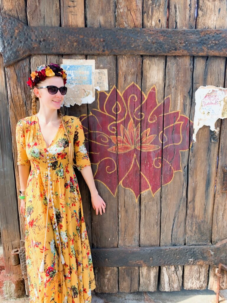 A woman in a yellow, floral dress stands in front of a mural, enjoying Animal Kingdom for adults. 