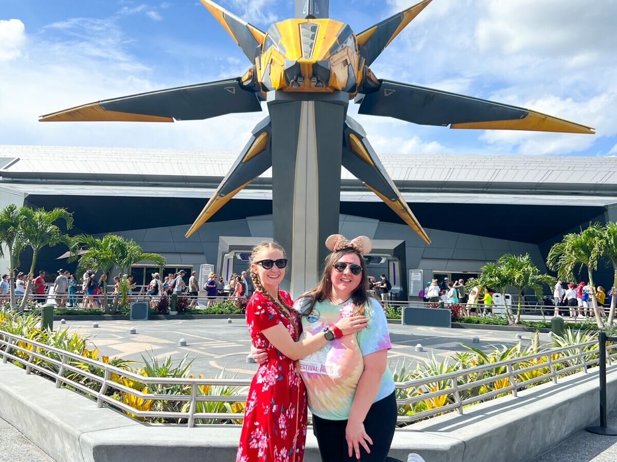 women posing in front of spaceship-shaped statue