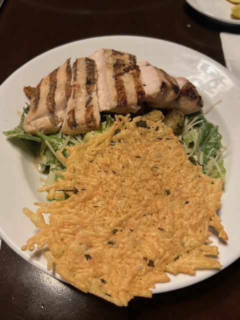 grilled chicken on a salad with large parmesan crisp at mama melrose Hollywood studios for adults 