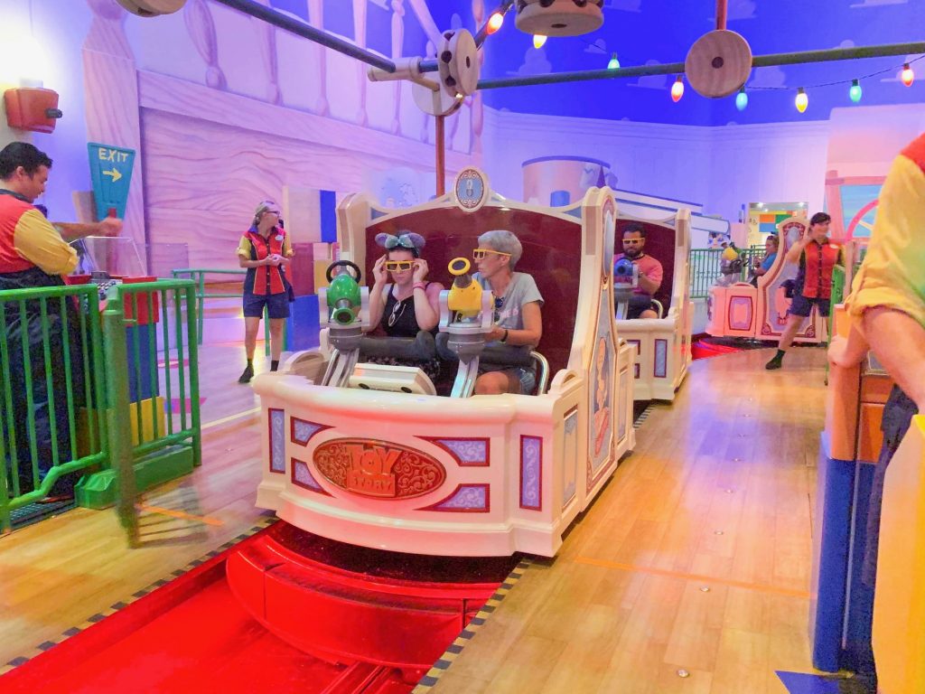 people in a ride vehicle wearing 3d glasses in a toy themed ride 
