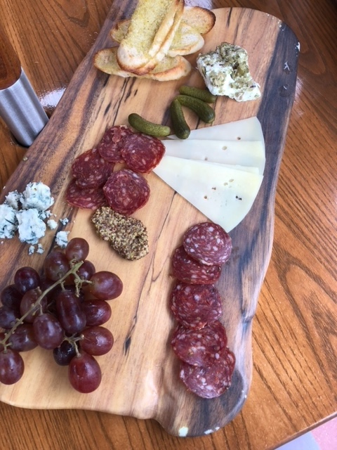 meat, cheese, grapes and crackers on a board 
