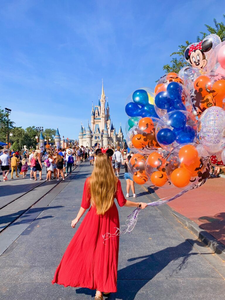 woman standing in a red dress and mickey ears at disney world