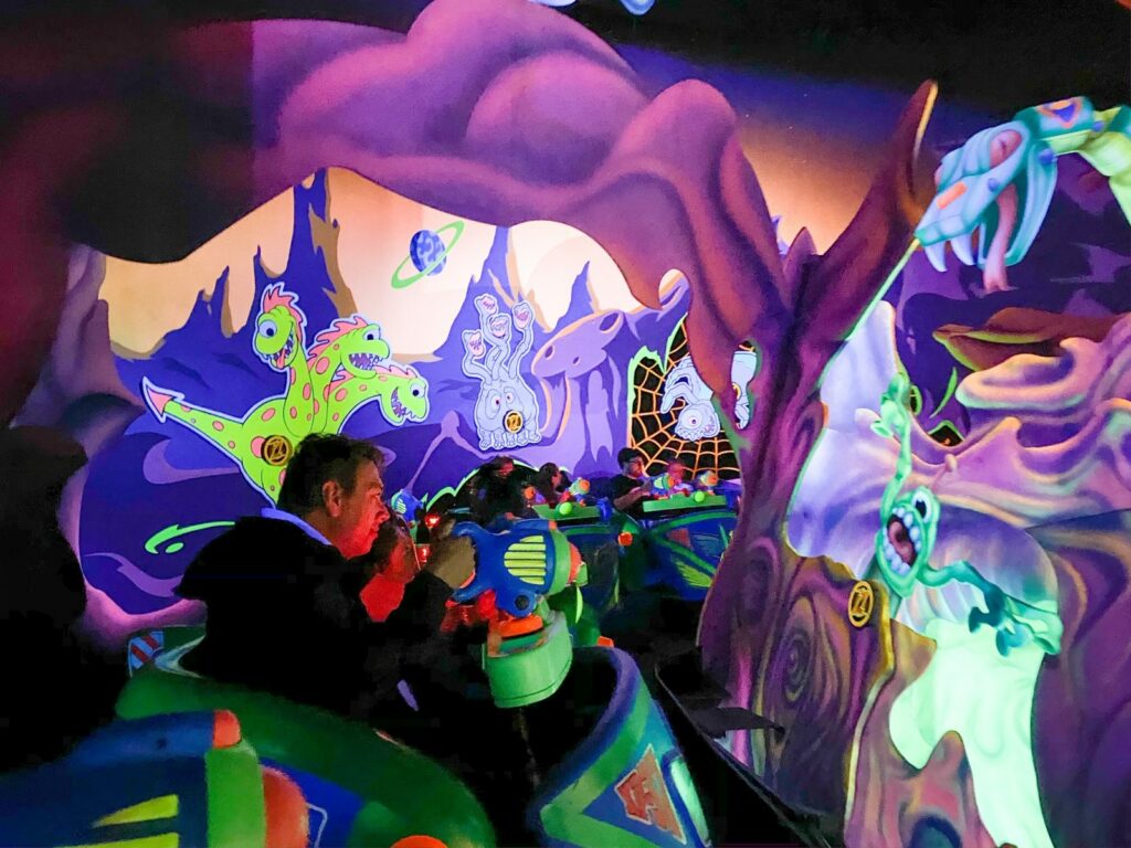 Adults hunch over and shoot to win on Buzz Lightyear's game, which is full of aliens, bright colors and spins.