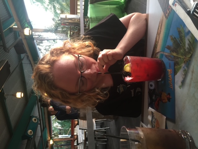 A girl with blonde hair leans over a raspberry margarita at Margaritaville in Orlando, which is not one of the best restaurants at Universal Orlando. The drinks are the only good thing! 