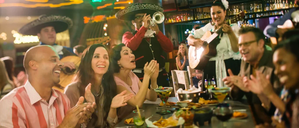 Guests gather around a table as a band plays, enjoying authentic tacos, guac, and margs at Antonjitos. 