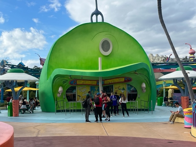 green building housing quick service restaurant at universal orlando with people standing outside of it