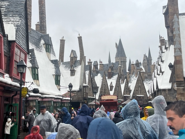 In the tight space of Hogsmeade, guests in ponchos, hats and rain jackets still walk in an open area, enduring the drizzle but knowing there is shelter in the snow capped buildings nearby. 